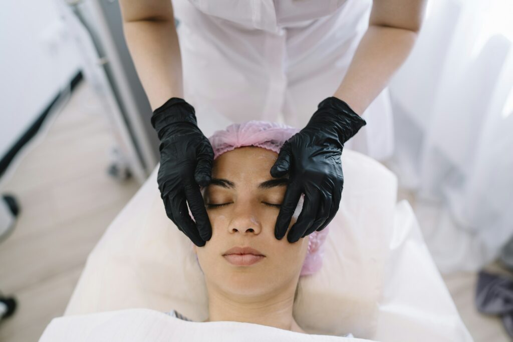 Faceless cosmetologist massaging face of lady